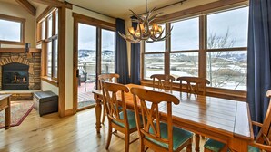 Uma sala de jantar com uma mesa e cadeiras de madeira, um candelabro e uma lareira.