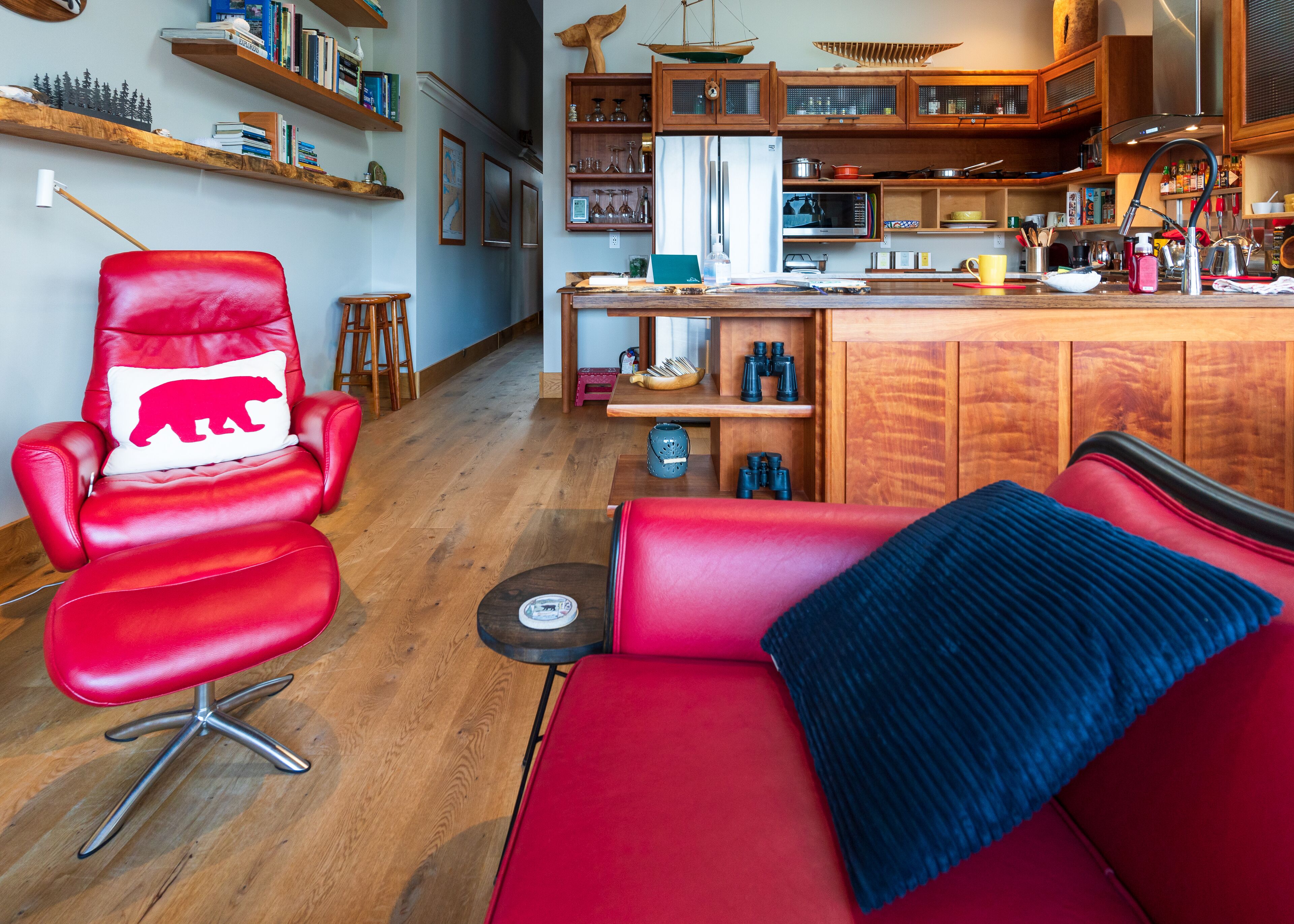 Un salón moderno con un sillón de cuero rojo, un sofá rojo y suelo de madera.