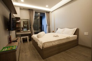 A hotel room with a bed, a desk with a computer, a TV, and a small table with a magazine. - Trang's Apartment (Ho Chi Minh City)