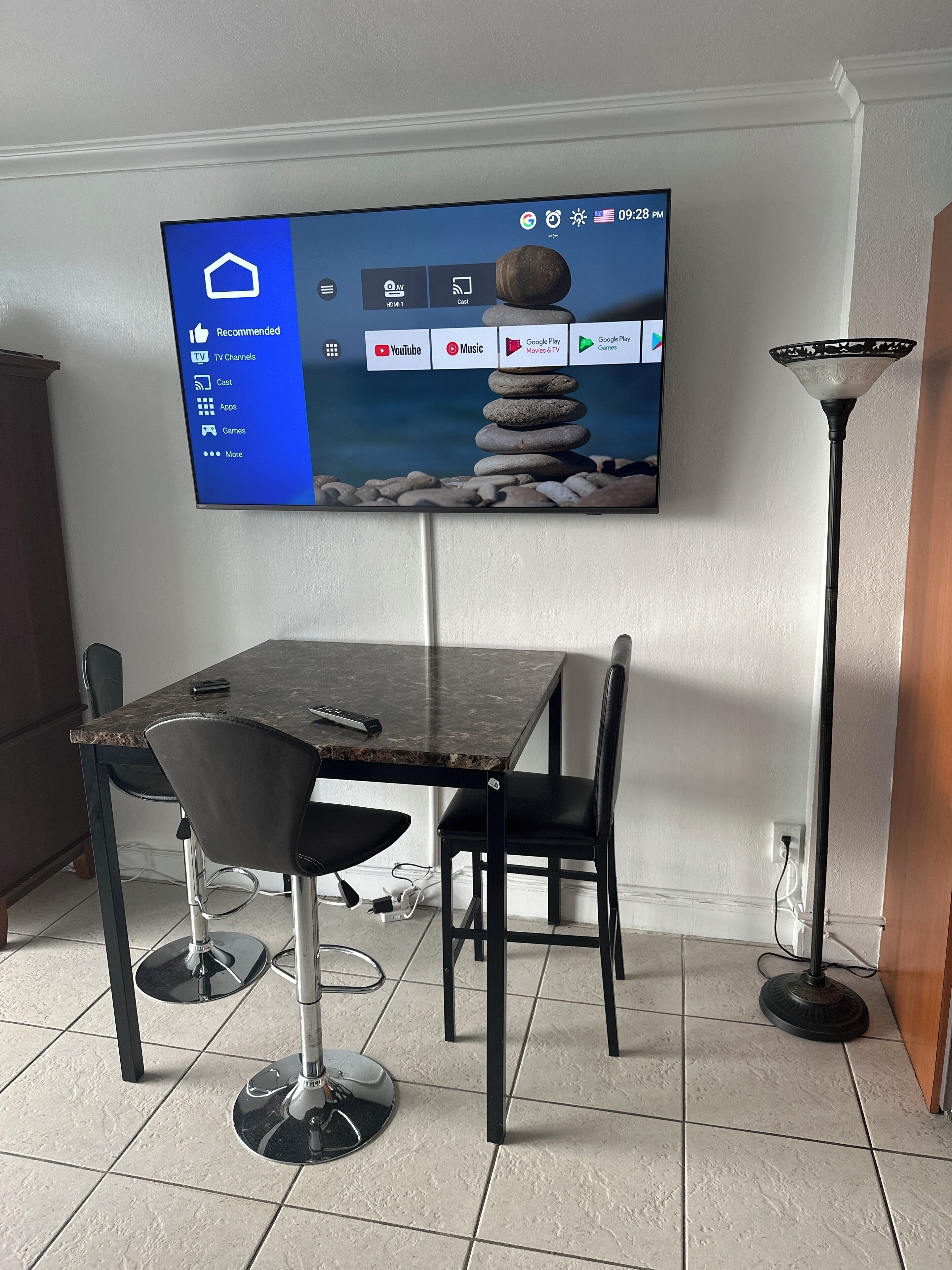 A modern dining area with a TV mounted on the wall displaying a home screen.