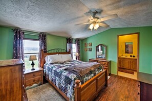 A bedroom with a wooden bed, a nightstand, a dresser, a ceiling fan, and a window with curtains.