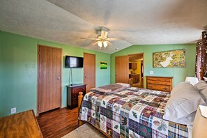 Un dormitorio con una cama de madera, ventilador de techo, televisor y pared verde.