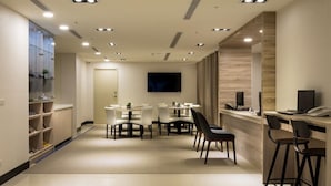 Un vestíbulo de hotel moderno con un mostrador de recepción, zona de estar y una pantalla de televisión.