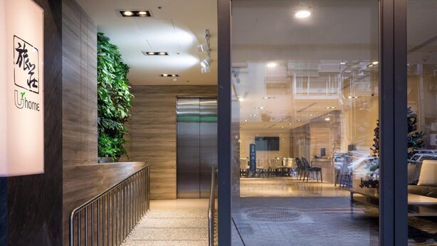 Un moderno vestíbulo de hotel con mostrador de recepción, jardín vertical y vistas al área interior con asientos.