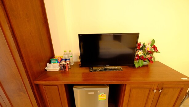 A wooden entertainment center with a television, a small refrigerator, and a trash bin. - The Muk Lagoon (Mukdahan)