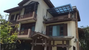 Un bâtiment à deux étages, doté d’un balcon à l’étage supérieur, d’un porche couvert au rez-de-chaussée et d’une grande fenêtre en verre sur le côté supérieur droit.