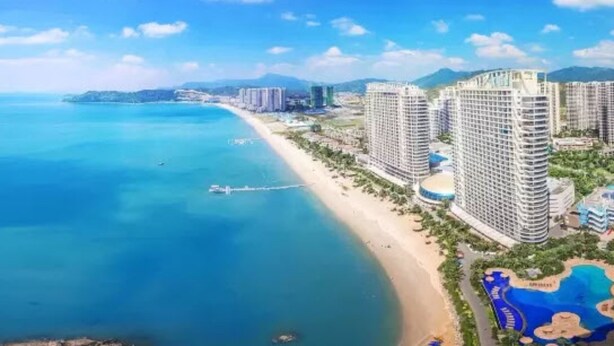 Una zona turística costera con edificios altos, una playa y un parque acuático.