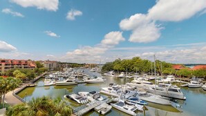 Marina con varias embarcaciones amarradas, rodeada de edificios y vegetación.