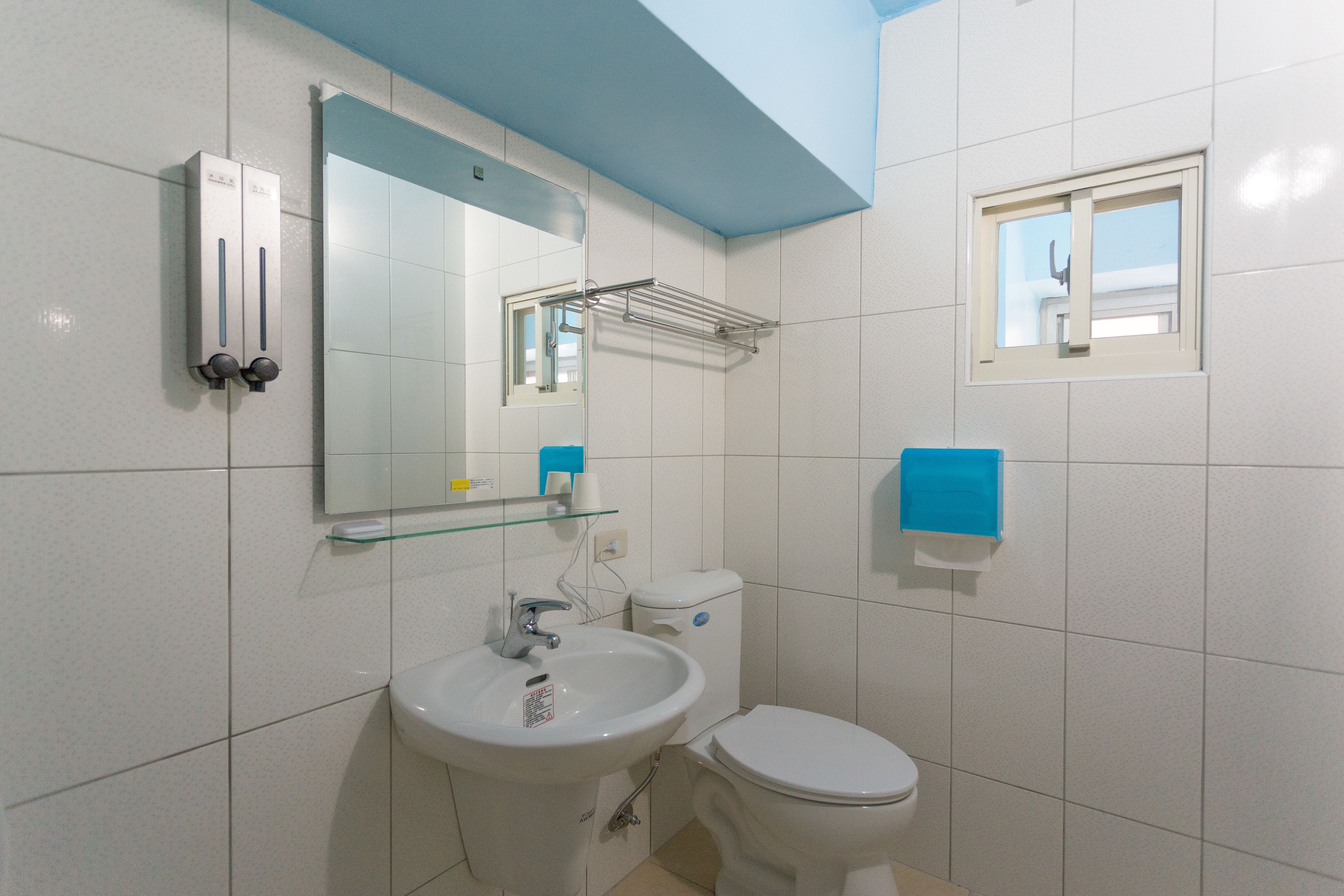A bathroom with a white sink, a mirror, a toilet, and a window.
