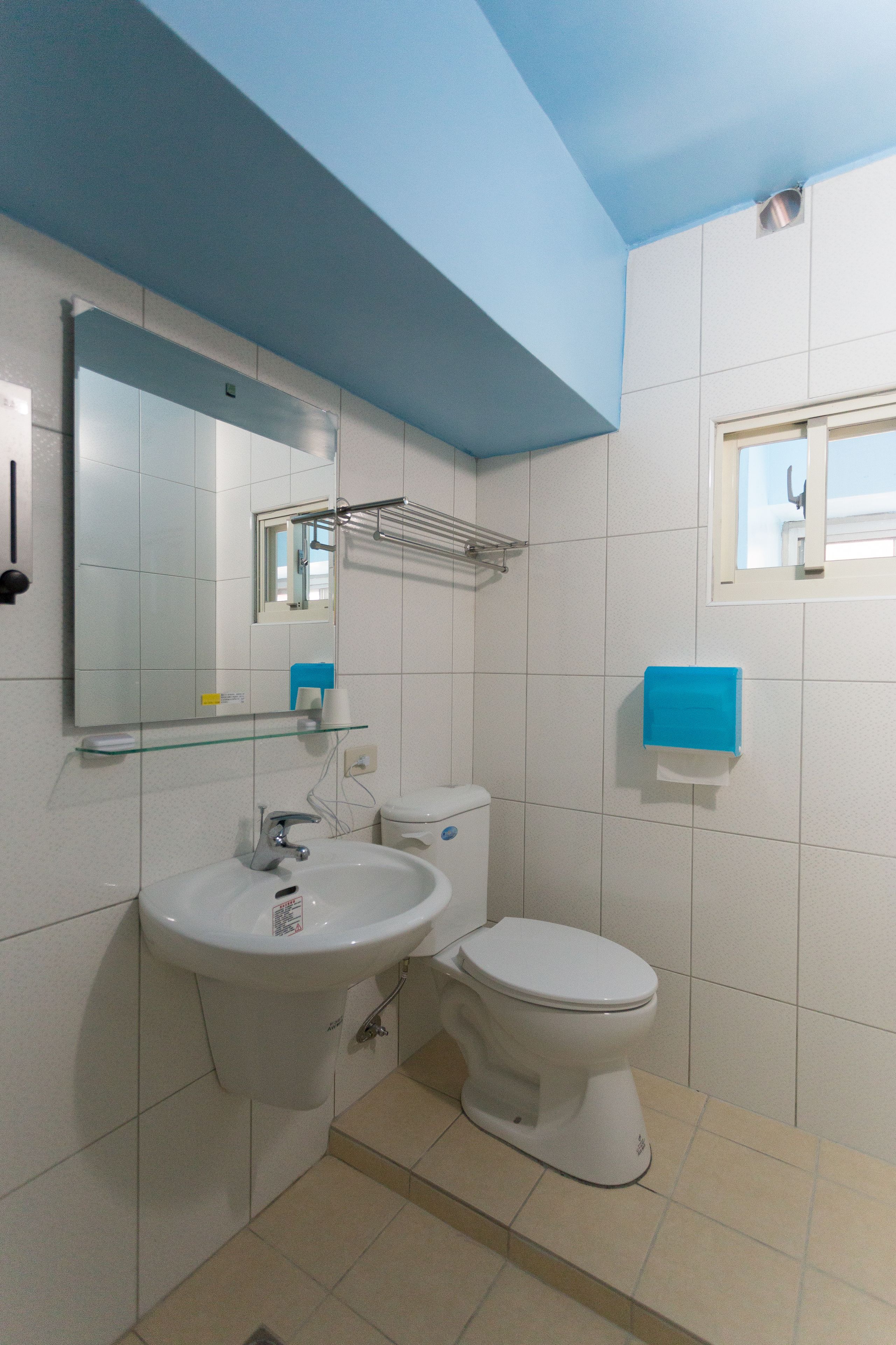 A bathroom with a white sink, a toilet, and a mirror.