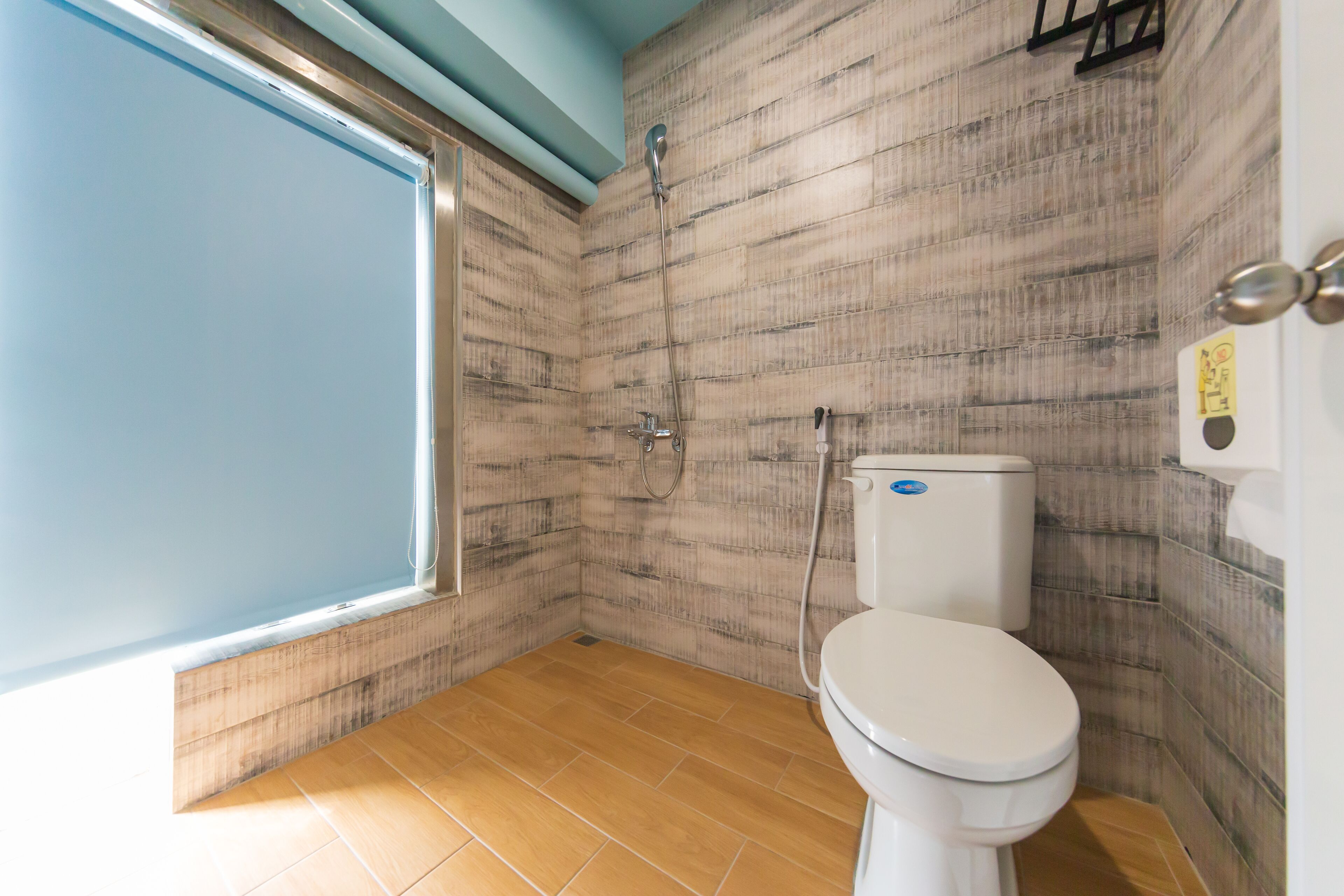 A bathroom with a toilet, shower, and a window.