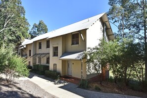 A two-story building with a sloped roof, a front porch, and a small front yard.