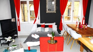 Ein modernes Schlafzimmer mit Bett, Nachttisch, Fernseher und einem Essbereich mit Stühlen und Tisch.