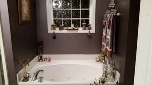 Ein Badezimmer mit einer großen Badewanne, einem Fenster und verschiedenen Pflegeprodukten auf der Fensterbank.