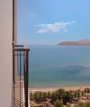 A balcony with a view of a beach and ocean. - Majestic Premium Hotel (Nha Trang)