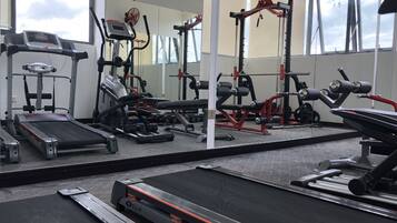 Un gimnasio con diversos equipos de ejercicio, incluyendo cintas de correr, máquinas de pesas y pesas libres.