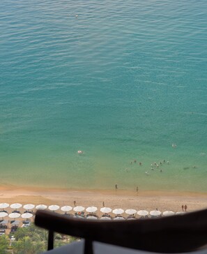 A beach with clear water, umbrellas, and people. - Majestic Premium Hotel (Nha Trang)