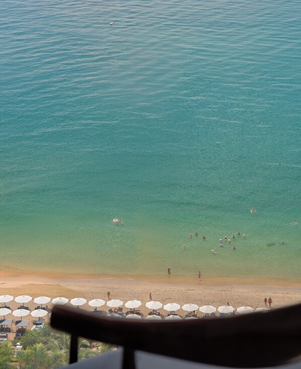 A beach with clear water, umbrellas, and people.