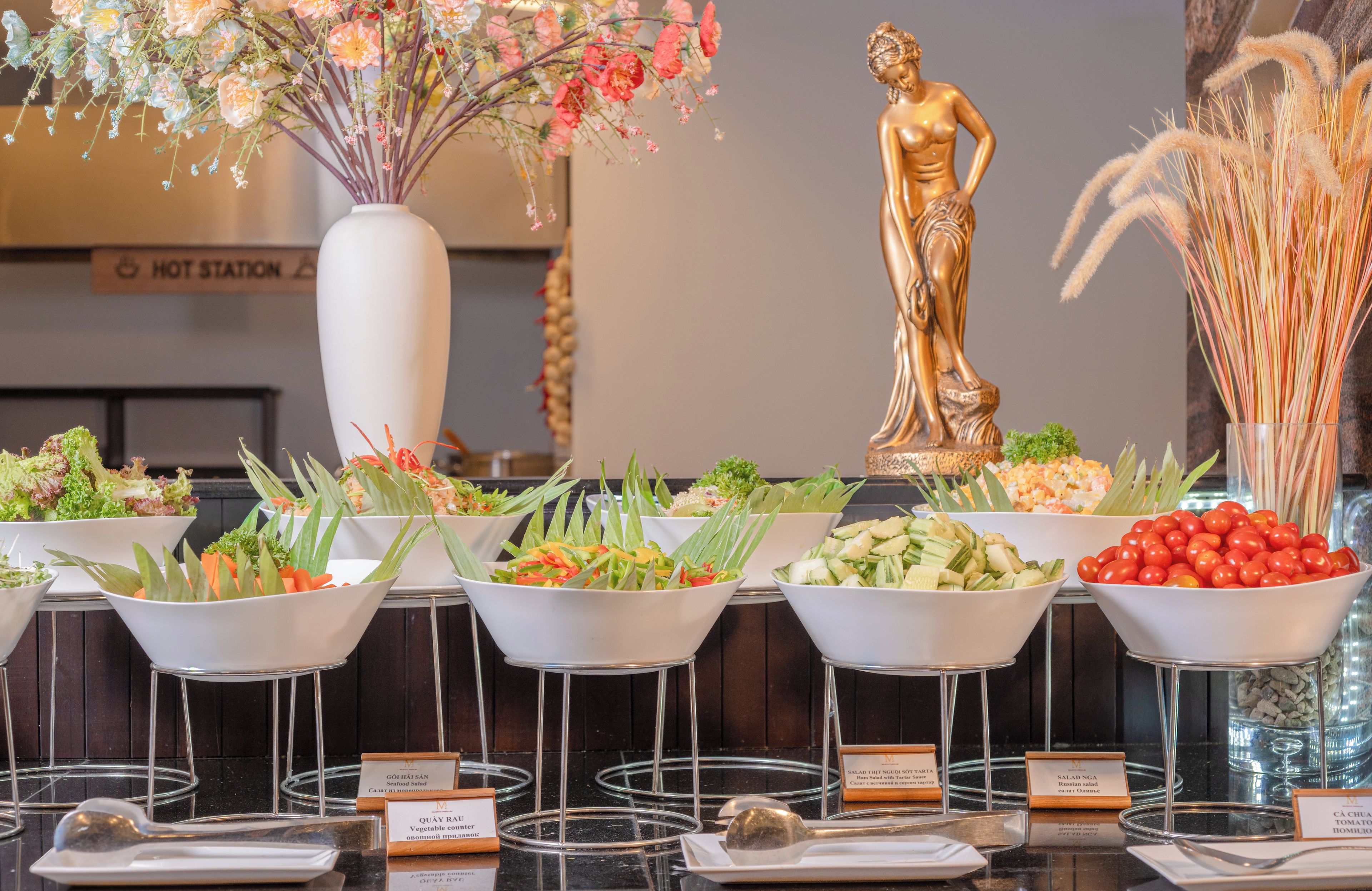 A buffet with various salads and a decorative golden statue.