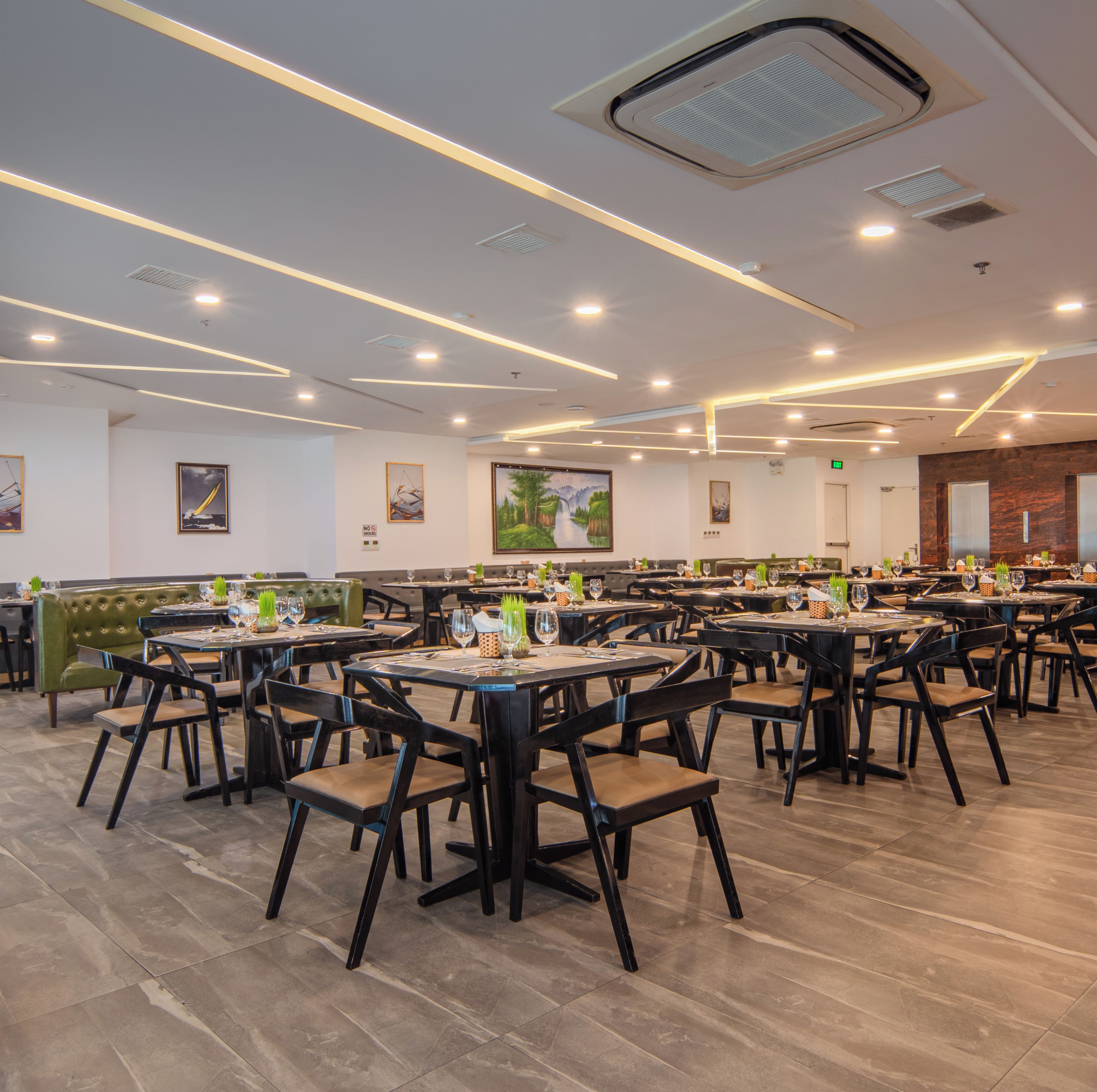A spacious restaurant with multiple dining tables and booths, equipped with modern lighting and ceiling vents.
