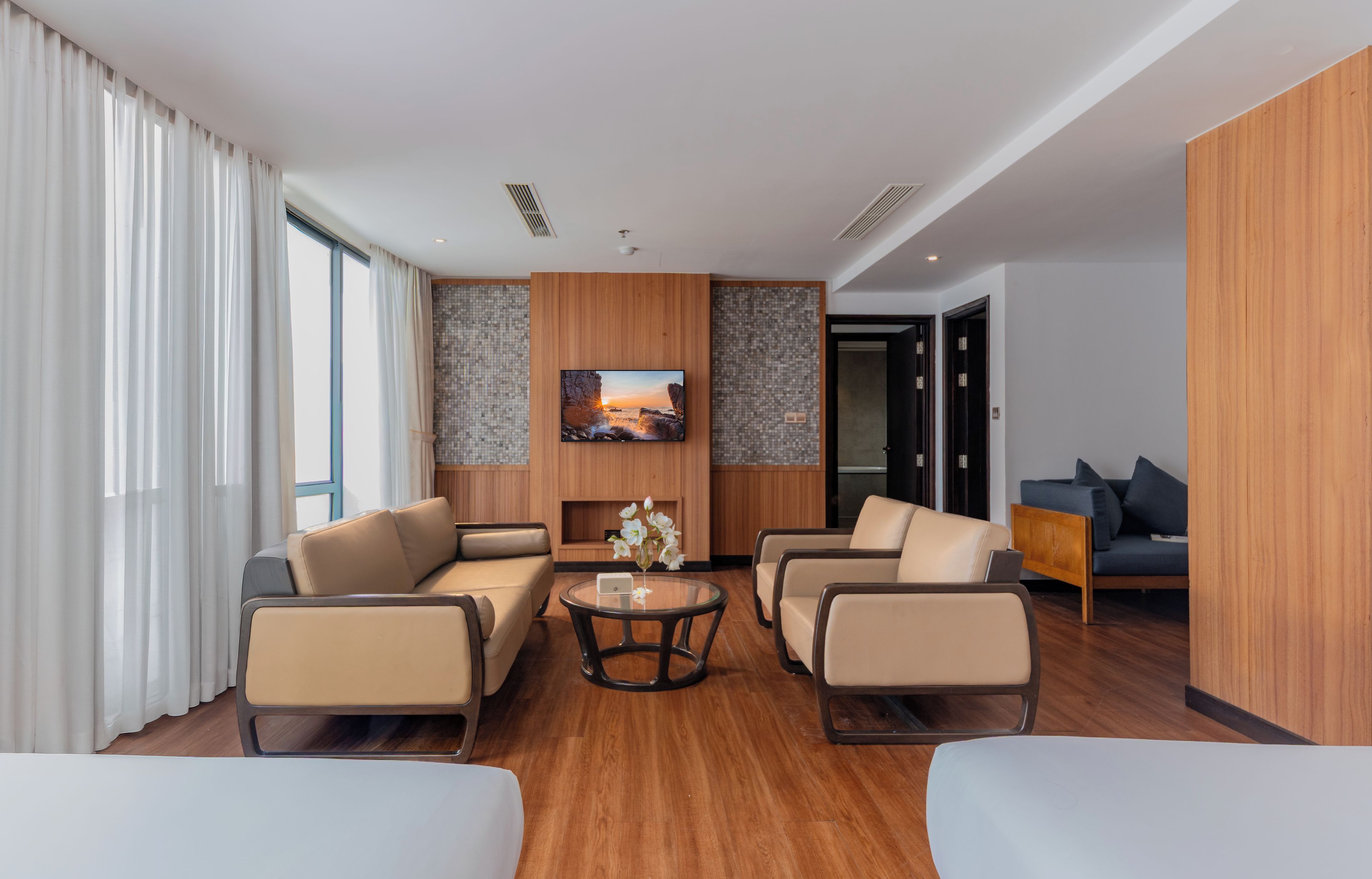 A modern hotel room with a sofa set, a coffee table, and a painting on the wall.