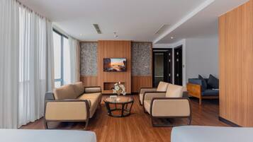 A modern hotel room with a sofa set, a coffee table, and a painting on the wall.