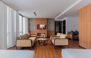 A modern hotel room with a sofa set, a coffee table, and a painting on the wall. - Majestic Premium Hotel (Nha Trang)