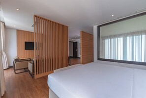 A hotel room with a bed, a desk, a chair, a TV, and a large window with curtains. - Majestic Premium Hotel (Nha Trang)