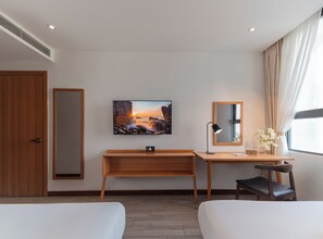 Een hotelkamer met een bed, een bureau, een stoel, een televisie en een raam met gordijnen.