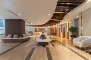 A modern hotel lobby with a reception desk, seating areas, and a curved ceiling design. - Majestic Premium Hotel (Nha Trang)