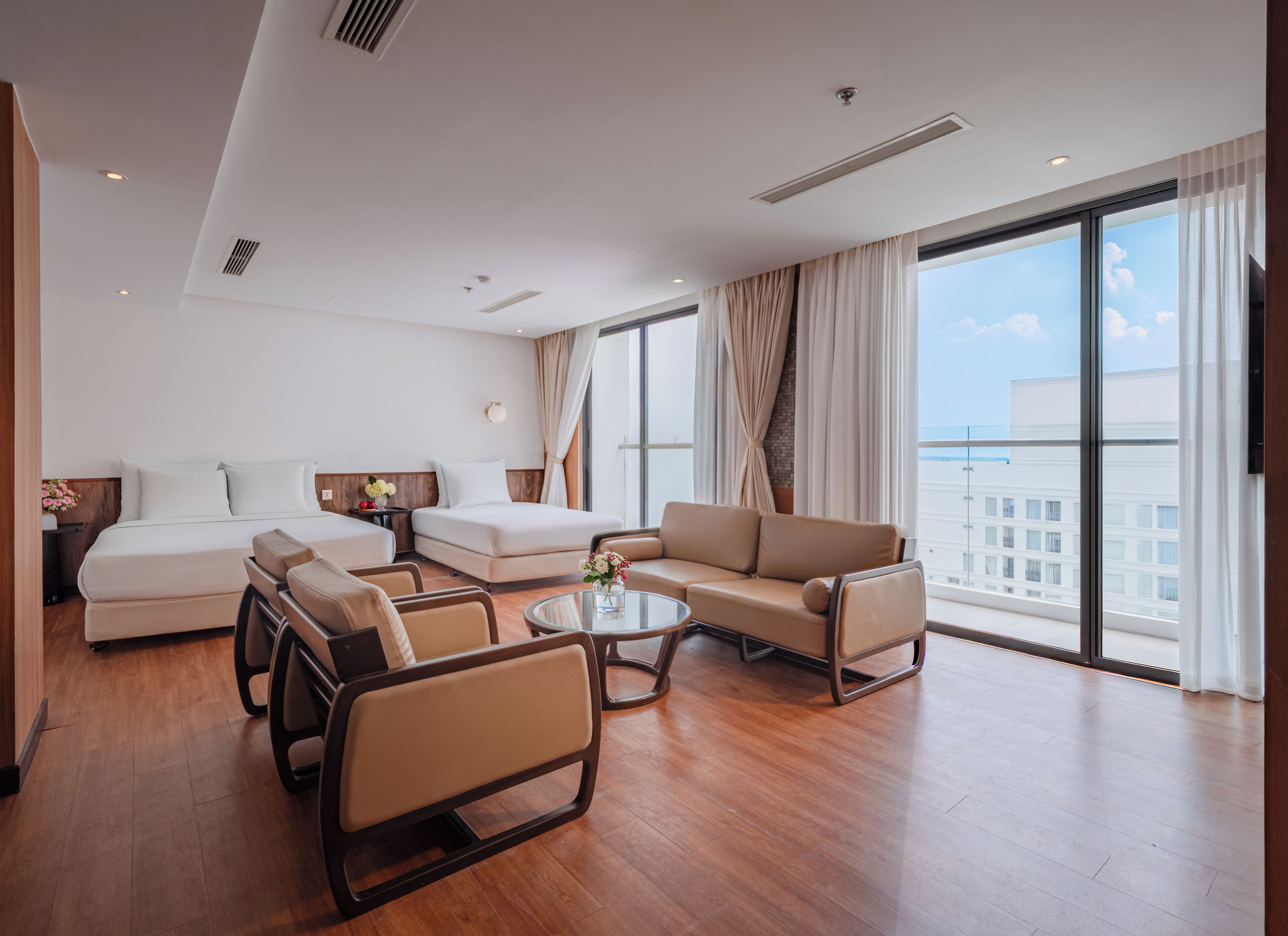 A hotel room with a bed, sofa, armchair, and a table.
