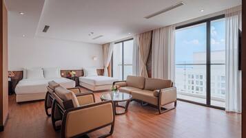 A hotel room with a bed, sofa, armchair, and a table.