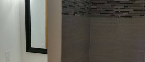 A bathroom with a white bathtub, a showerhead, and a sink with a mirror above it.