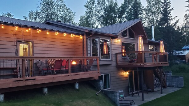 Une cabane en bois dotée d’une terrasse, de meubles d’extérieur et d’une cheminée.
