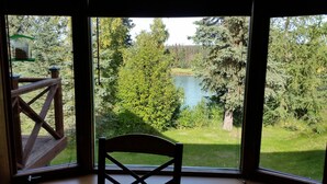 Une pièce dotée d’une grande fenêtre donnant sur un lac, entourée d’une forêt dense.