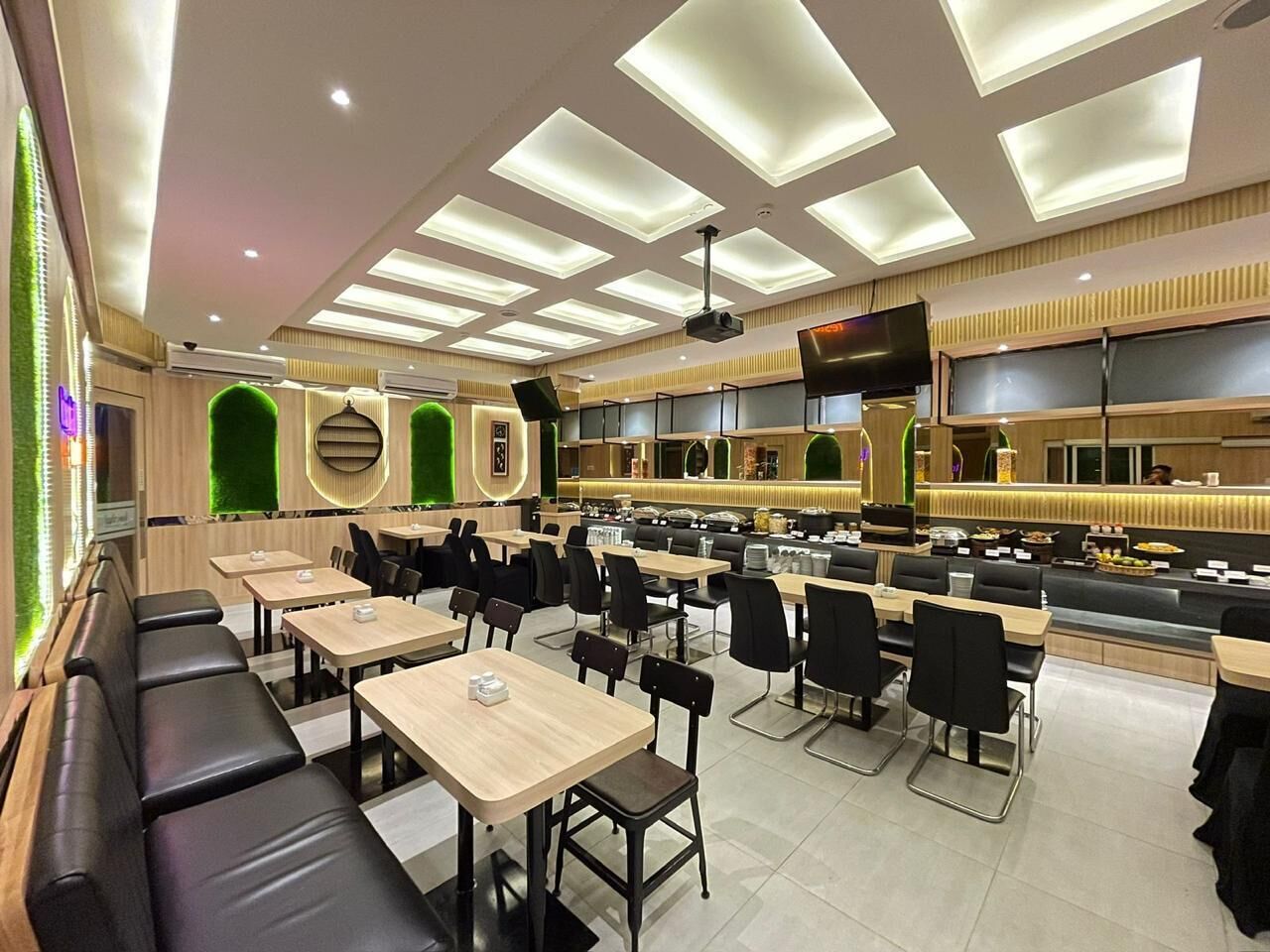 A modern restaurant with multiple seating areas, including booths and tables, and a counter with a display of food items.