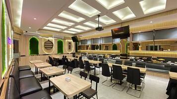A modern restaurant with multiple seating areas, including booths and tables, and a counter with a display of food items.