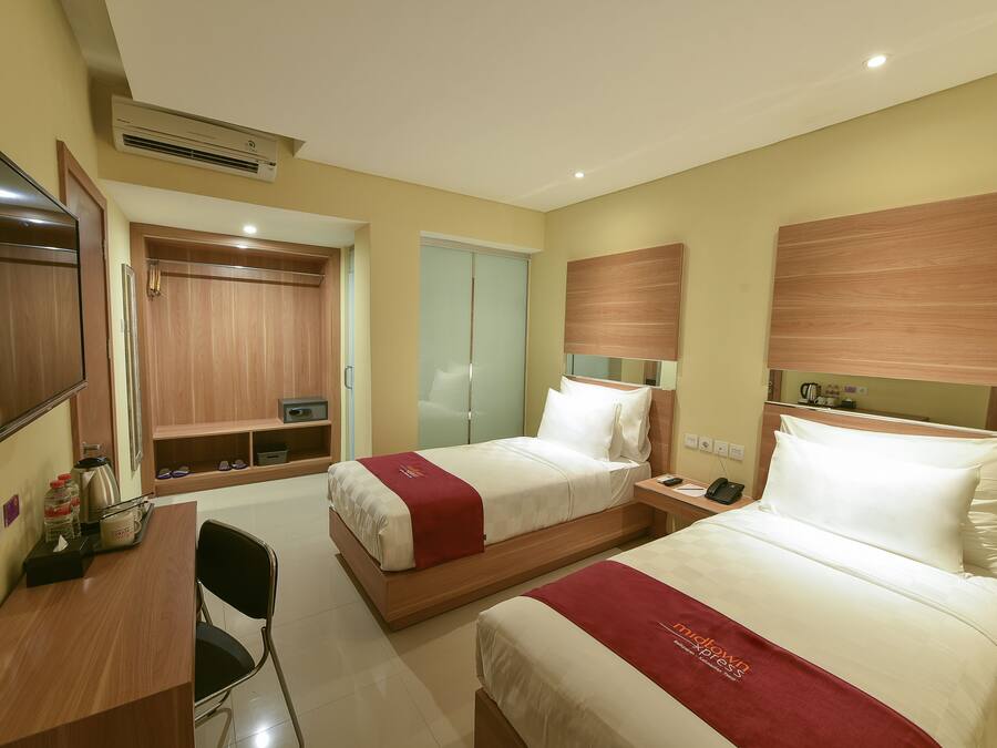 Een hotelkamer met twee bedden, een bureau en een kledingkast.