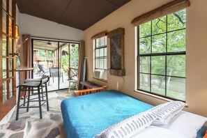 A room with a bed, a desk, and a window with a view of trees.