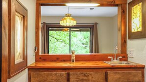 Un tocador de madera con espejo, lavabo e iluminación colgante.
