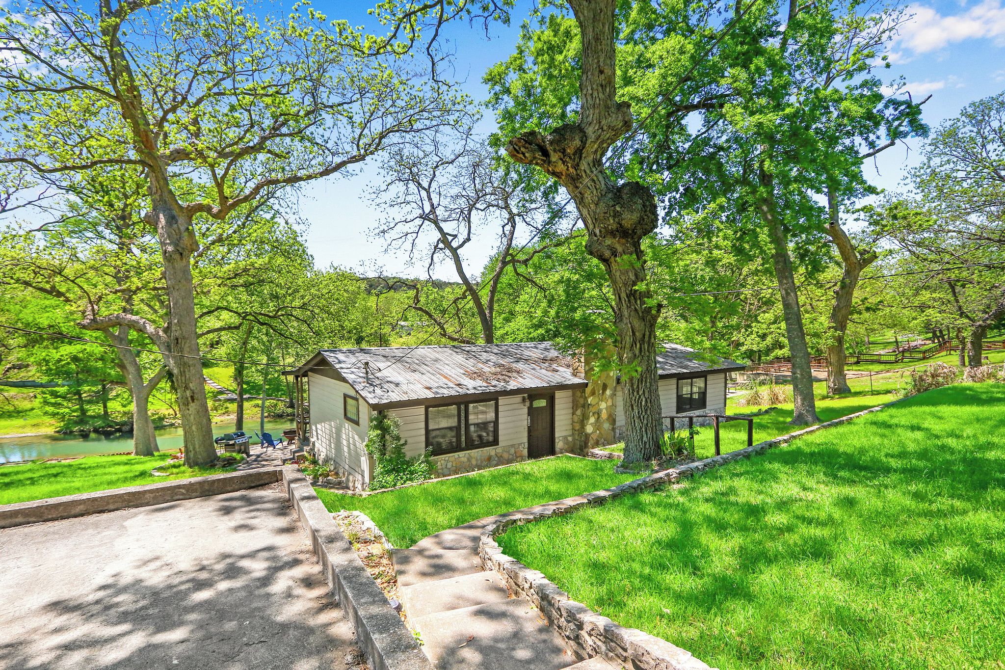 A rustic cabin with a stone foundation, surrounded by lush green grass and trees.