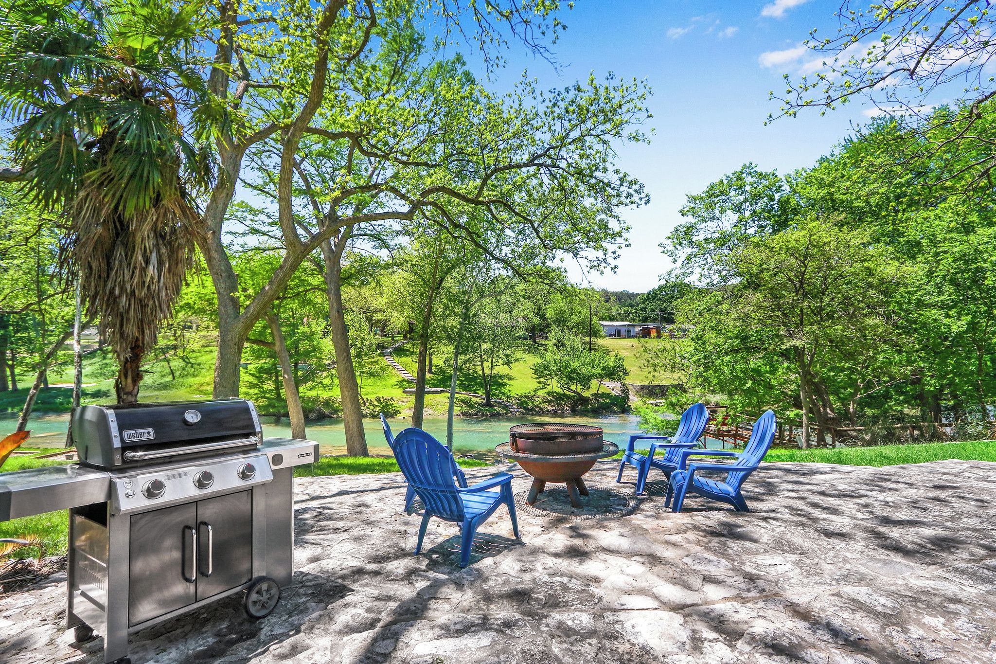 Ein Außenbereich mit Grill, zwei Adirondack-Stühlen und einer Feuerstelle.