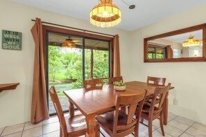 A dining area with a wooden table and chairs, a hanging light fixture, a window with curtains, and a mirror on the wall. - The Guadalupe River right in your backyard! River living at its best! (New Braunfels)