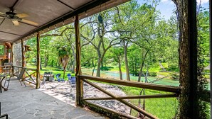 Un espacio al aire libre techado con vistas a un paisaje verde exuberante, suelo de piedra y mobiliario exterior.