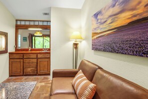 A living room with a brown leather sofa, a stone floor, a wooden cabinet, a lamp, and a painting of a lavender field. - The Guadalupe River right in your backyard! River living at its best! (New Braunfels)