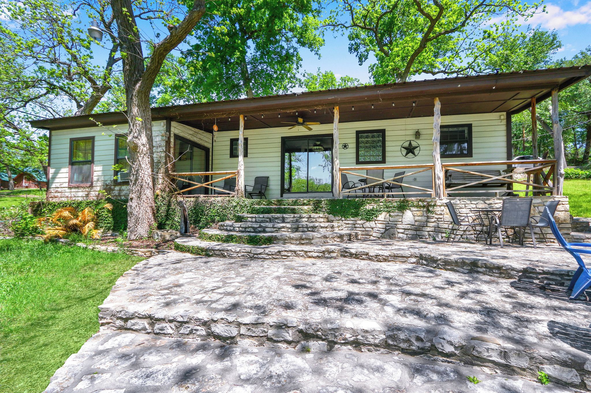 Une maison avec un porche, des marches en pierre et du mobilier d’extérieur.