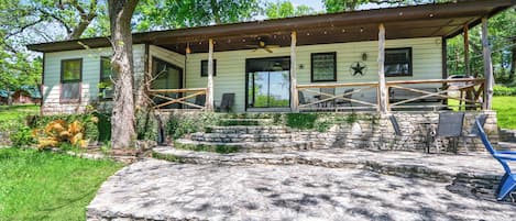 Una casa con porche, escalones de piedra y mobiliario exterior.