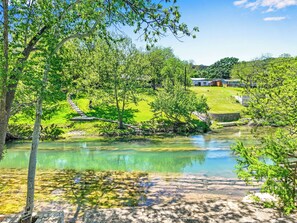 A serene lakeside setting with a clear view of a small building and a pathway leading to it.