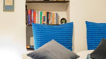 Une chambre à coucher avec un lit, des oreillers, une bibliothèque et un objet décoratif accroché au mur.
