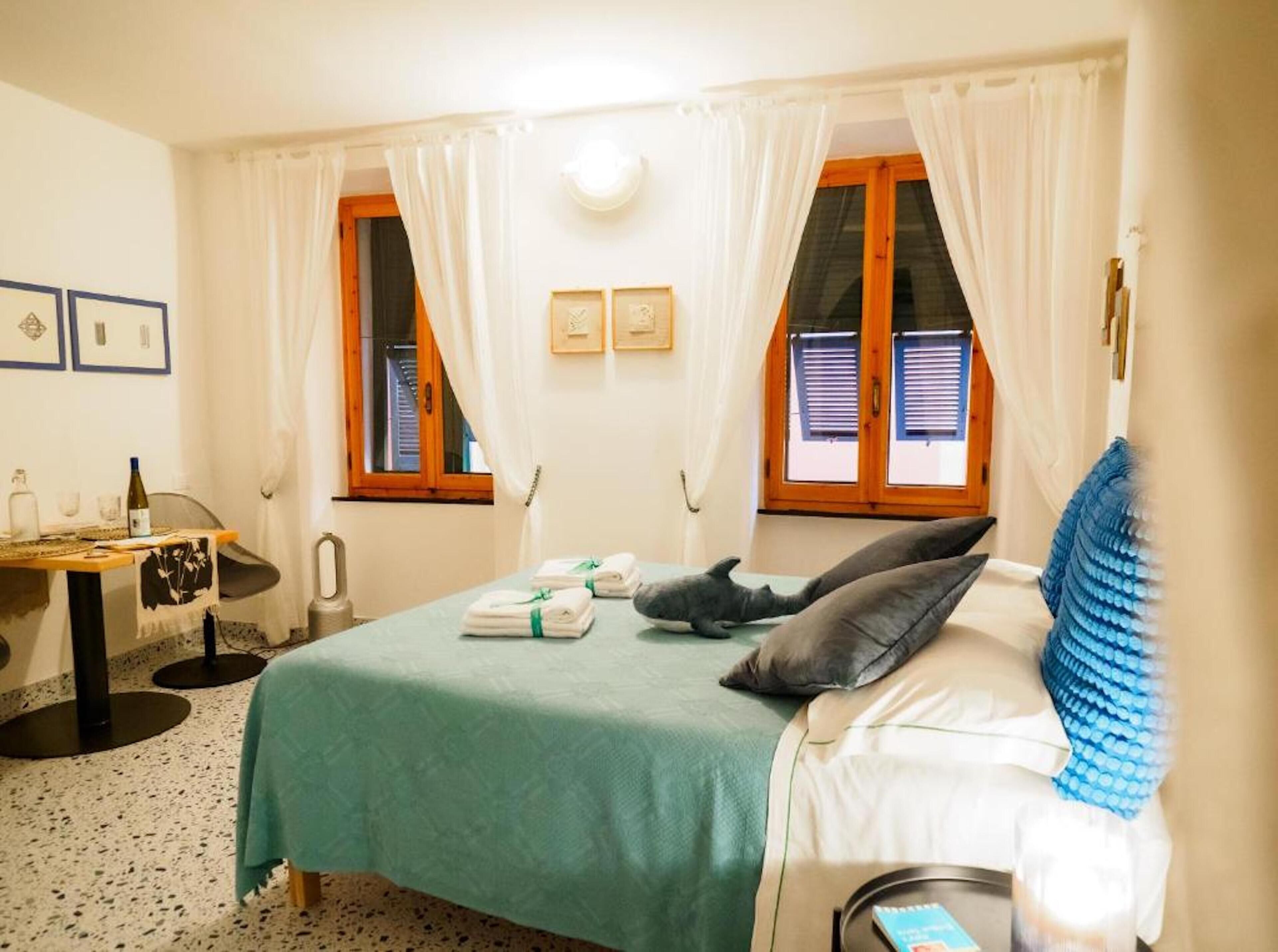 Una habitación de hotel con cama, escritorio y dos ventanas con cortinas.